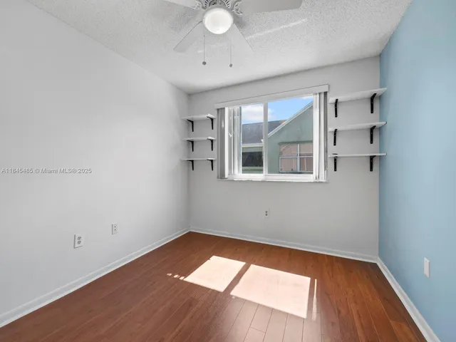 an empty room with wooden floor and ceiling fan