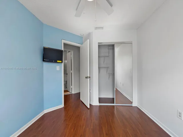 an empty room with wooden floor fan and windows