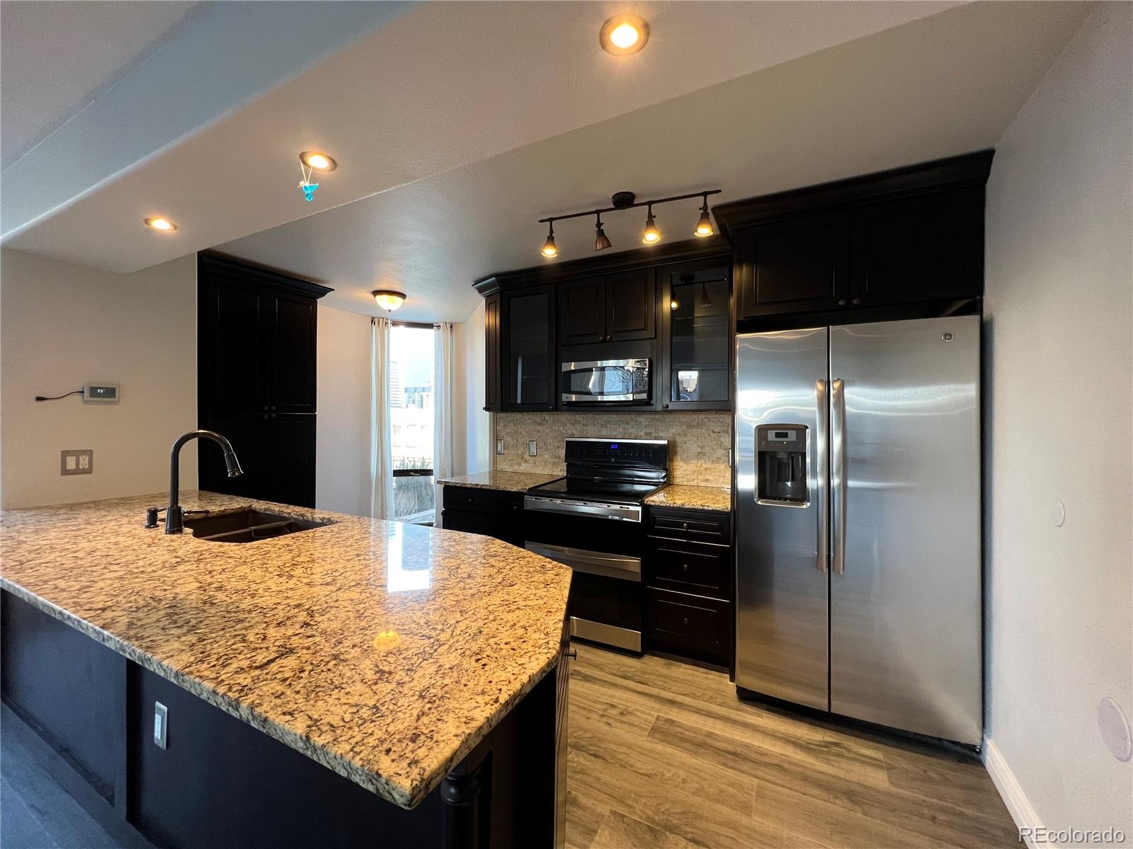 a kitchen with granite countertop kitchen island stainless steel appliances a refrigerator sink and microwave