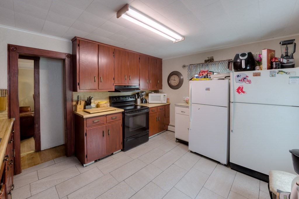 92 Mill Street Lancaster, MA 01523 - Photo 11 of 42 a kitchen with cabinets a refrigerator and a stove top oven