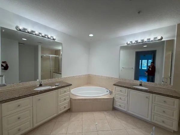 a bathroom with a granite countertop bathtub sink vanity and mirror