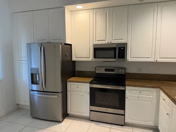 a kitchen with granite countertop white cabinets and stainless steel appliances