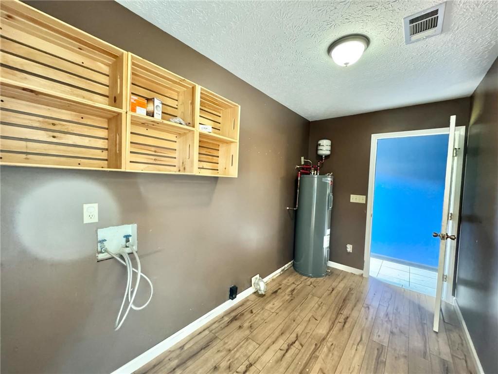 280 Owens Road Fort Mitchell, AL 36856 - Photo 21 of 56 Laundry room with water heater, wood-type flooring, baseboards, a textured ceiling, and hookup for a washing machine