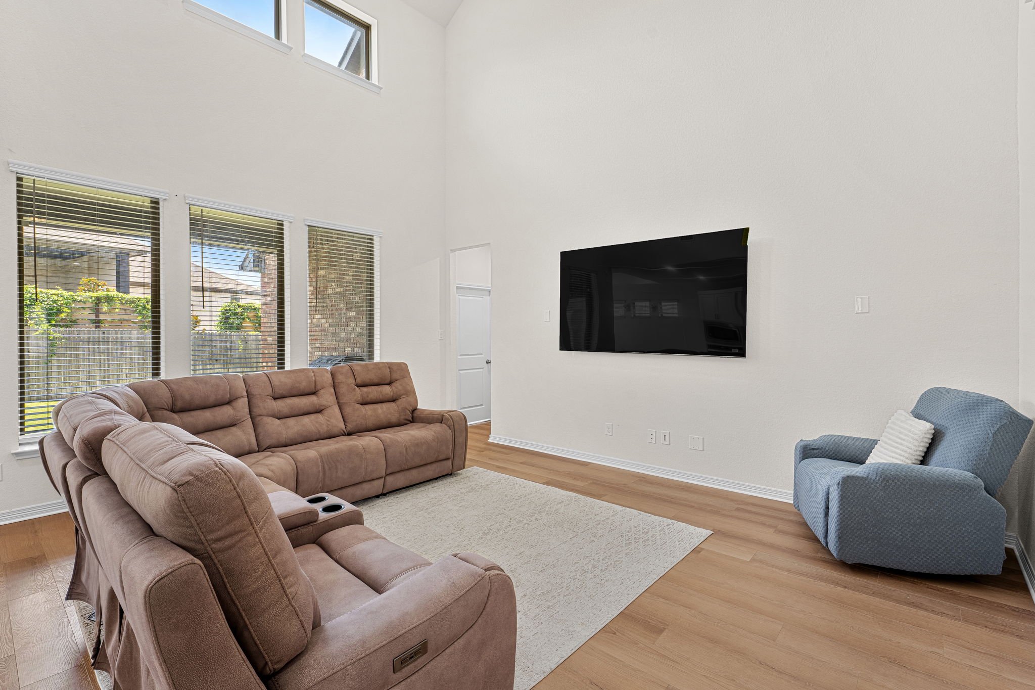 20813 Carries Ranch Road Pflugerville, TX 78660 - Photo 8 of 40 Double-height ceilings and tall windows frame this airy living space with warm wood floors.