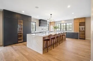 a large white kitchen with wooden floor and a sink