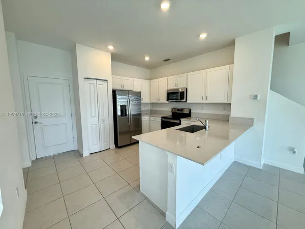 a kitchen that has a sink a refrigerator and a stove top oven
