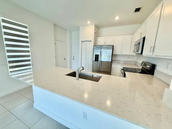 a large kitchen with stainless steel appliances granite countertop a sink a stove and a refrigerator