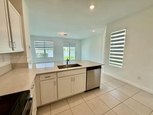 a kitchen with granite countertop white cabinets and window