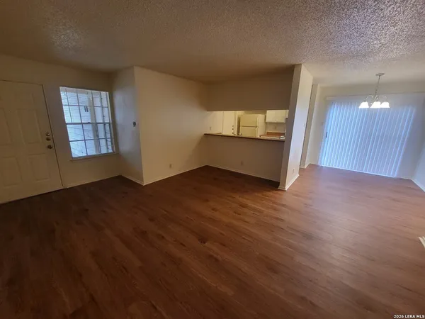 a view of an empty room with wooden floor and entryway