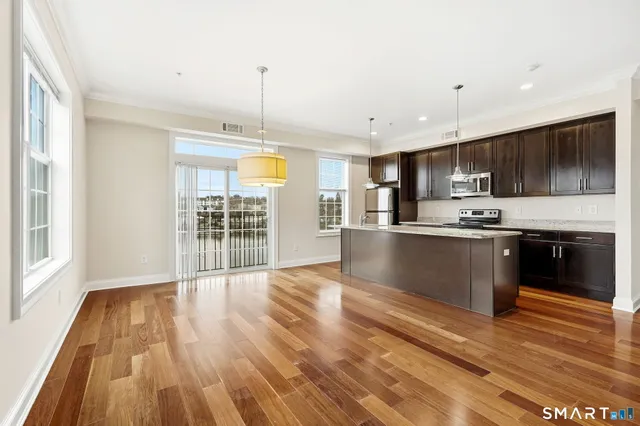 a large kitchen with stainless steel appliances granite countertop a stove and a wooden floors