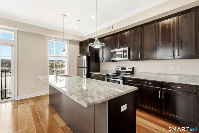 a kitchen with stainless steel appliances granite countertop a sink a stove and a refrigerator