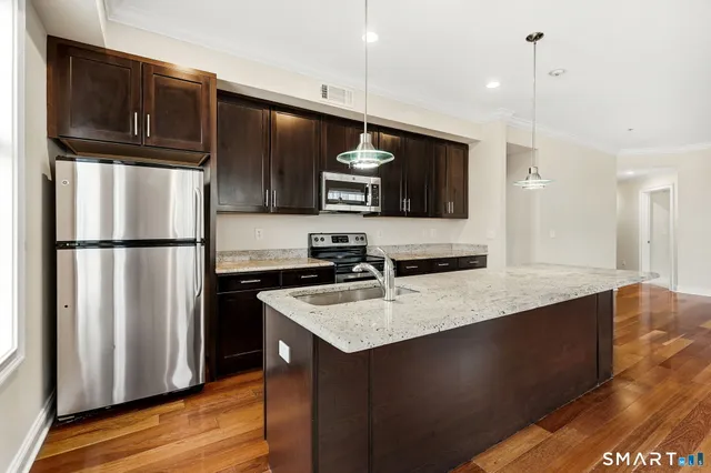 a kitchen with stainless steel appliances granite countertop a sink a refrigerator and a microwave