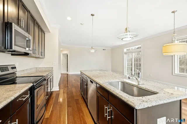 a kitchen with granite countertop a sink a counter space appliances and cabinets