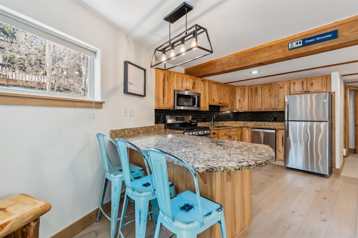 209 Miners Creek Road Frisco, CO 80443 - Photo 8 of 32 a kitchen with stainless steel appliances granite countertop a table chairs refrigerator and microwave