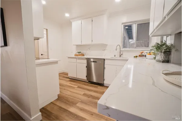 a kitchen with stainless steel appliances white cabinets and wooden floor