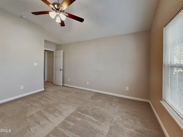 an empty room with windows and fan