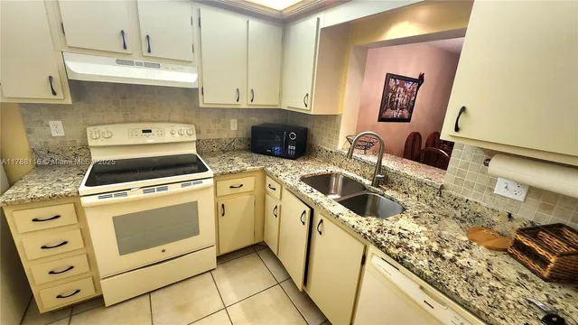 a kitchen with granite countertop a sink a stove and cabinets