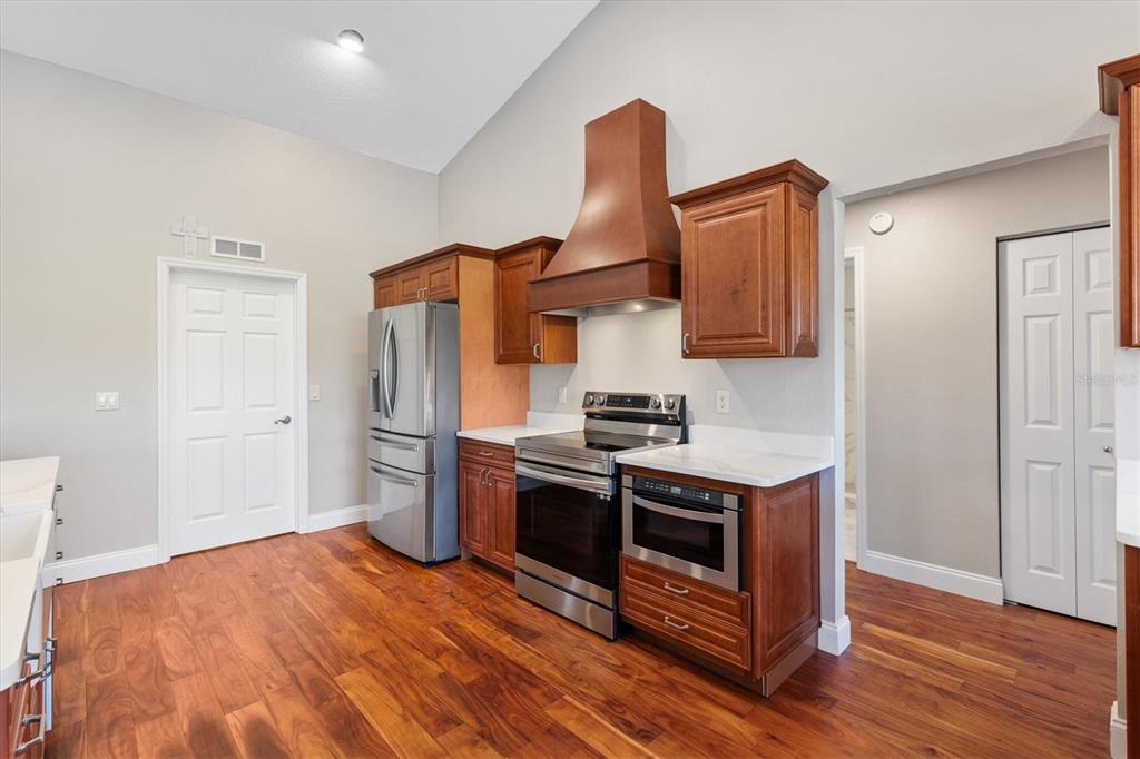 11735 Southeast 174th Loop Summerfield, FL 34491 - Photo 14 of 61 a kitchen with stainless steel appliances granite countertop a stove a refrigerator and a wooden floors