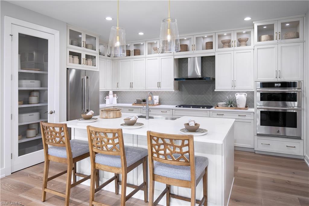 a kitchen with stainless steel appliances kitchen island granite countertop a dining table chairs sink and cabinets