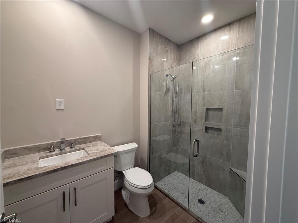8909 Oceana Way Naples, FL 34114 - Photo 19 of 41 a bathroom with a granite countertop sink a toilet and shower