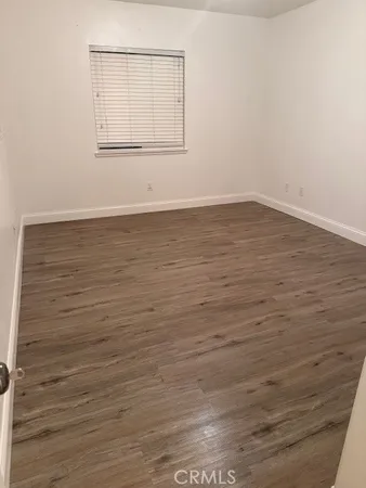a view of an empty room with wooden floor and cabinet