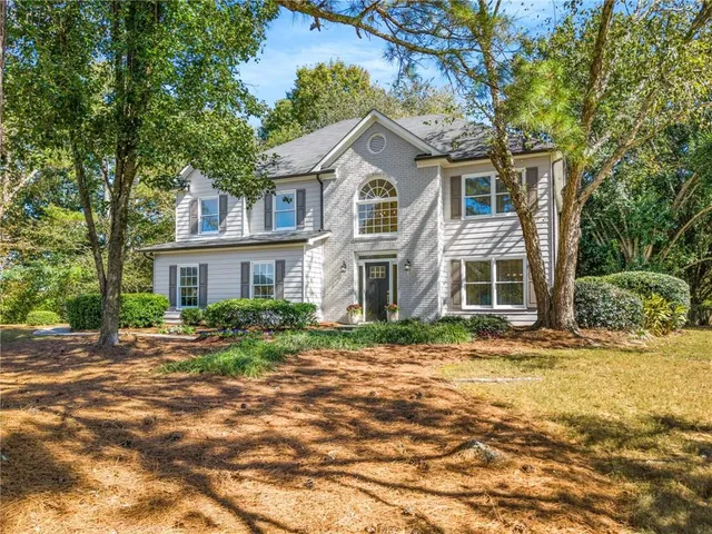 a view of a yard in front of a brick house with large windows