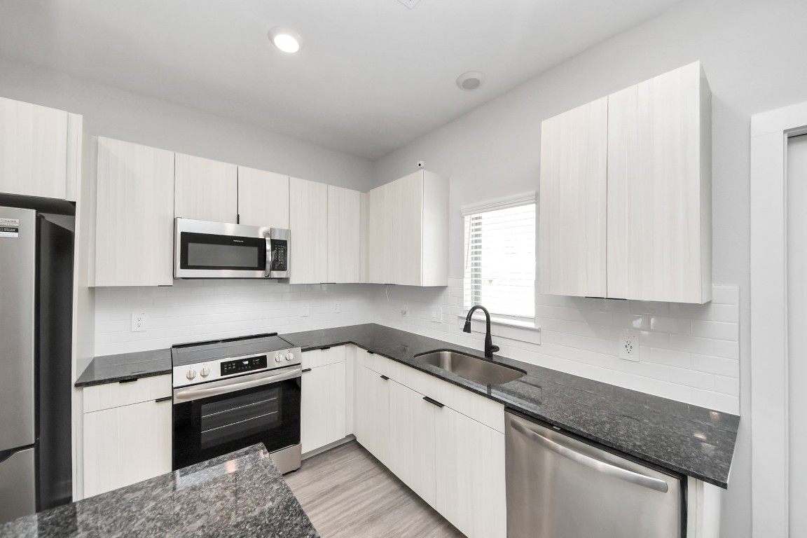 7711 Longmire Road, Unit 5 Conroe, TX 77304 - Photo 40 of 48 Boasting luxury finishes-stylish Island kitchen,granite counters,subway tile backsplash,ample custom cabinet space,stainless appliances,refrigerator,full size washer&dryer included,wood-like flooring throughout,open concept floor plan.