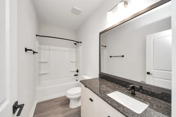 a kitchen with stainless steel appliances granite countertop a refrigerator a sink dishwasher a stove and white countertops with wooden floor
