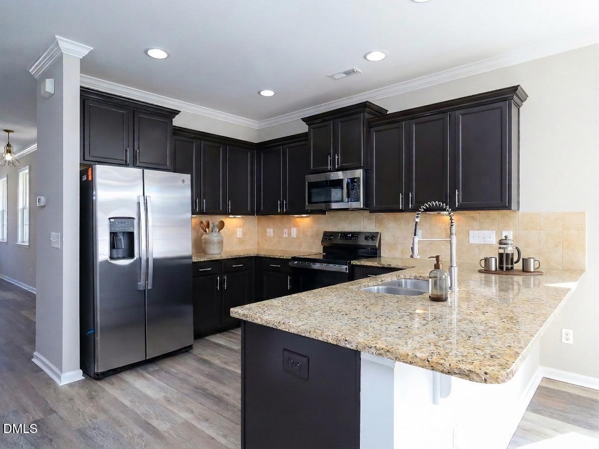 1314 Still Monument Way Raleigh, NC 27603 - Photo 8 of 25 a kitchen with kitchen island granite countertop a refrigerator a sink a stove a oven with wooden floor and cabinets
