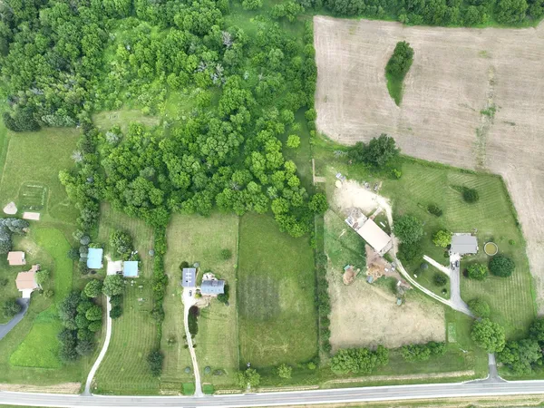 an aerial view of a residential houses with outdoor space and trees all around