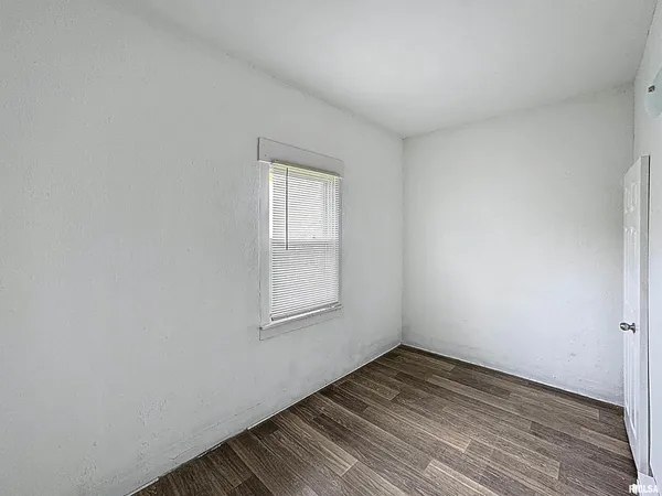 an empty room with wooden floor and mirror