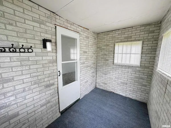a view of an empty room with brick wall and a window