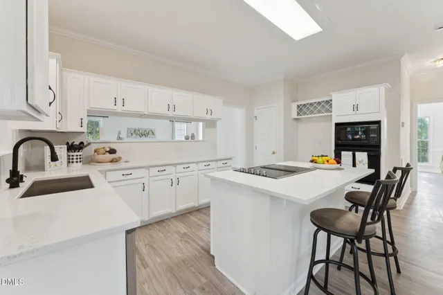 a large white kitchen with a large window a sink and stainless steel appliances