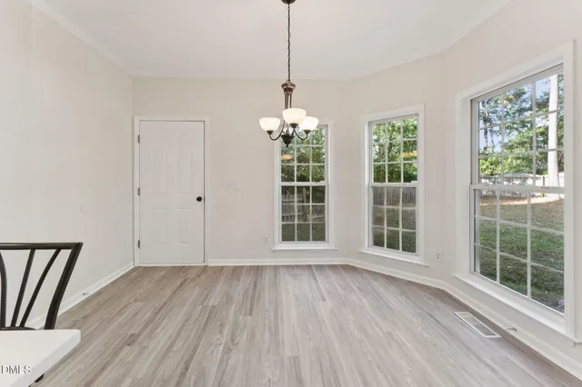 a kitchen with a table chairs refrigerator and wooden floor