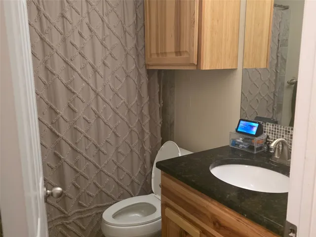 a bathroom with a granite countertop toilet and a sink