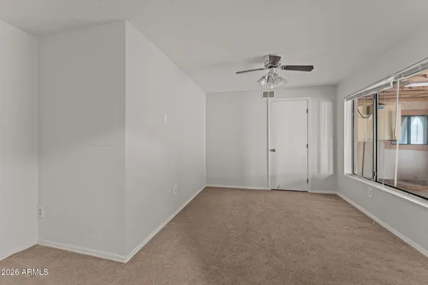 an empty room with windows and fan
