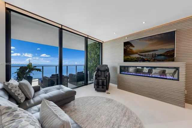 a living room with furniture a flat screen tv and a floor to ceiling window