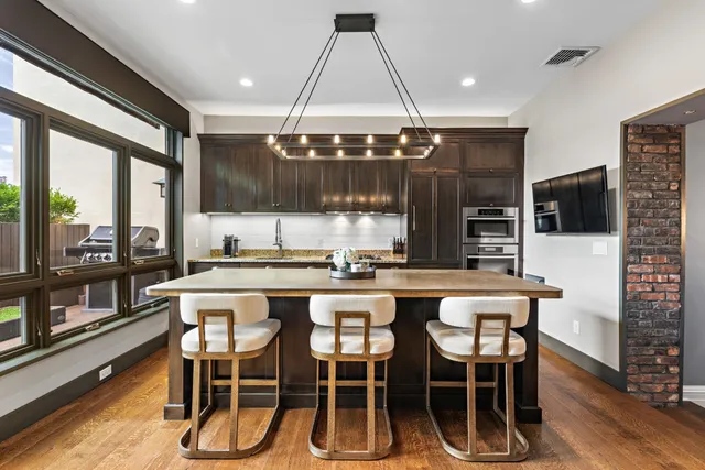 a dining room with stainless steel appliances kitchen island granite countertop a table chairs and a view of living room