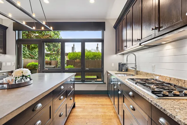a kitchen with stainless steel appliances granite countertop a sink a stove and a wooden cabinets