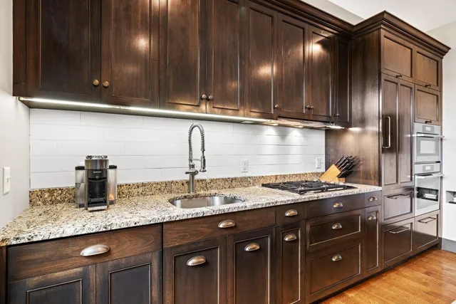a kitchen with granite countertop stainless steel appliances a sink stove and cabinets