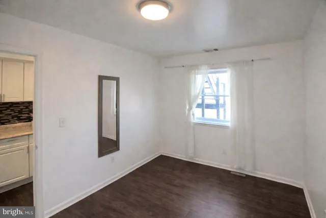 an empty room with wooden floor cabinet and windows