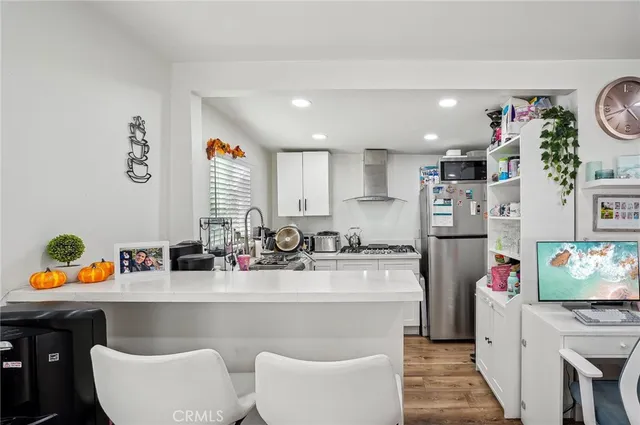 a kitchen with stainless steel appliances granite countertop a refrigerator a stove top oven a sink dishwasher and white cabinets with wooden floor