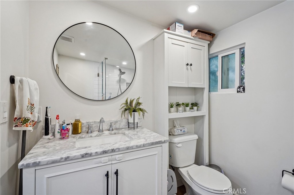 7251 Painter Avenue, Unit 7255 Whittier, CA 90602 - Photo 42 of 56 a bathroom with a granite countertop toilet a sink and a mirror
