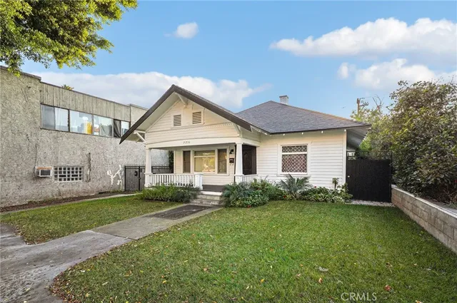 a view of a house with a yard plants and large tree