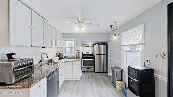 a kitchen with granite countertop a refrigerator a stove top oven a sink dishwasher and wooden cabinets