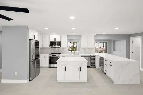 a large kitchen with white cabinets and stainless steel appliances