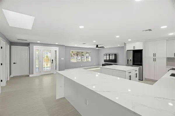 a large white kitchen with kitchen island a sink a stove and a refrigerator