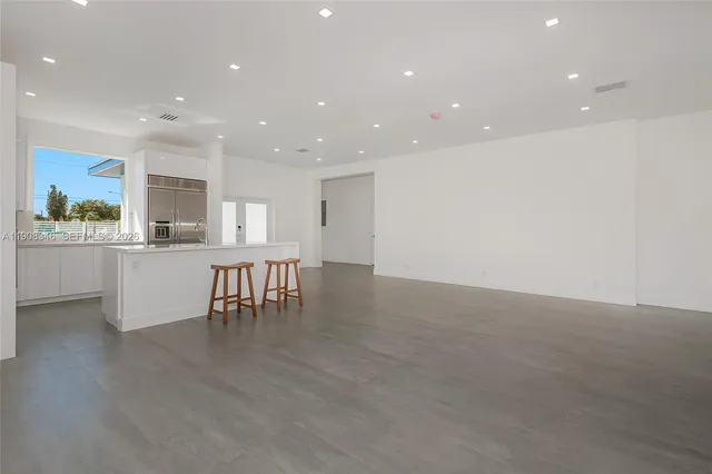 a kitchen with kitchen island stainless steel appliances a sink a stove a microwave a refrigerator and cabinets