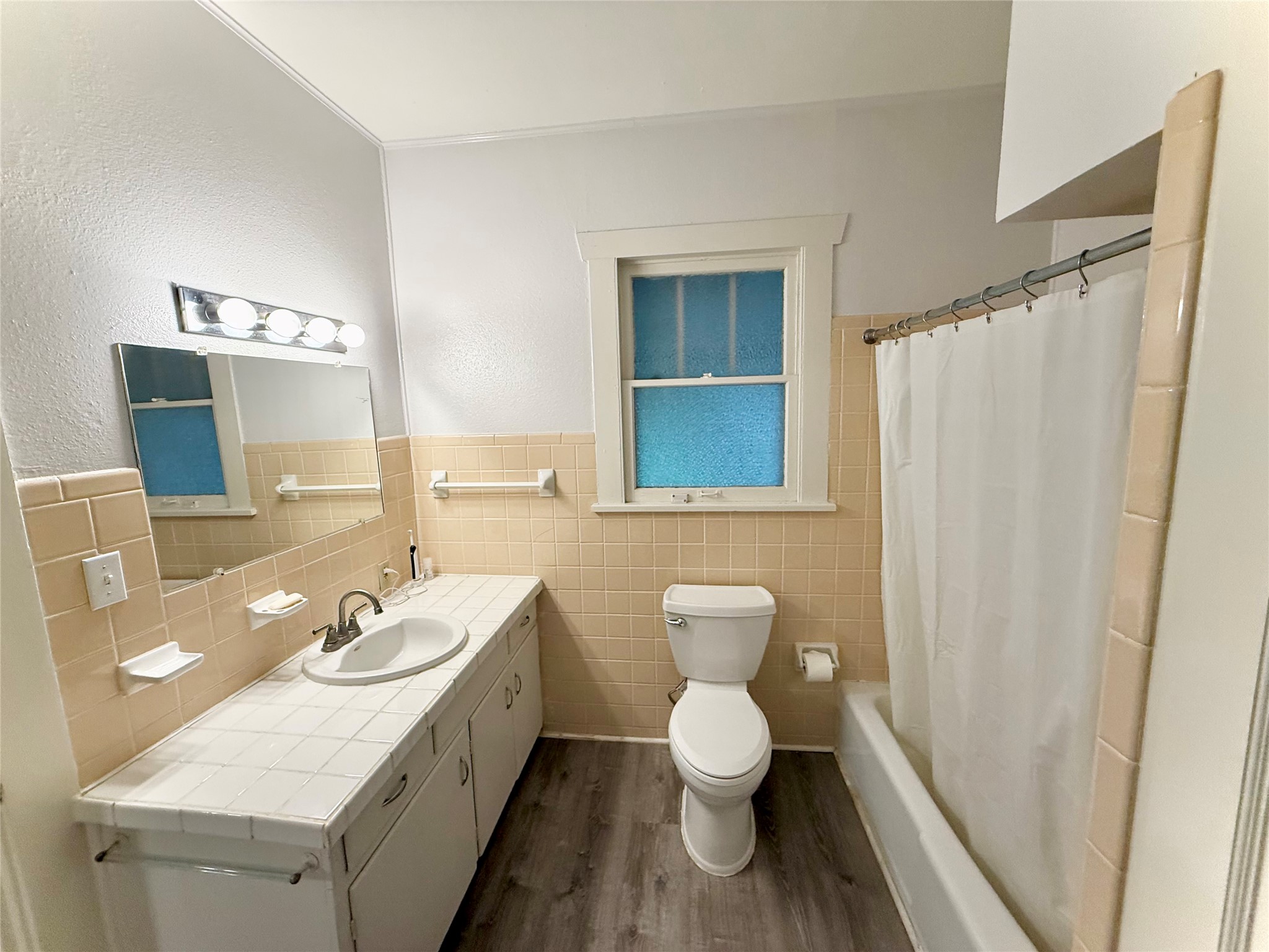 423 South Main Street Lockhart, TX 78644 - Photo 9 of 26 Bathroom with wood-finish flooring, a white bathtub, and a built-in vanity featuring a white sink and tiled countertop