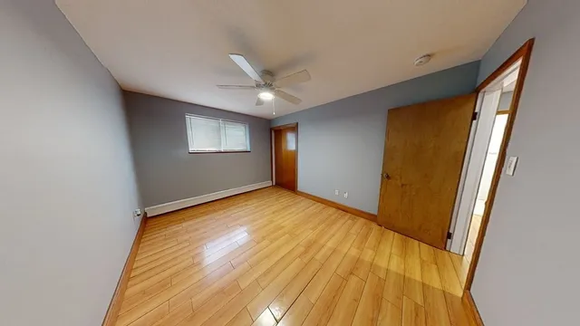 a view of empty room with wooden floor and fan